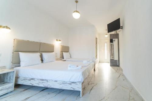 een witte slaapkamer met een groot bed en een flatscreen-tv bij Amalthia in Skala Potamias
