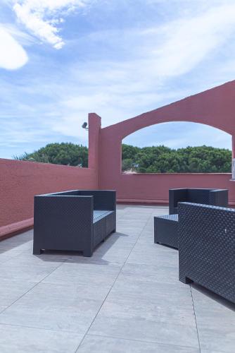 a patio with three benches and a red wall at The Originals City, Relax'Otel & Spa, Le Barcarès in Le Barcarès