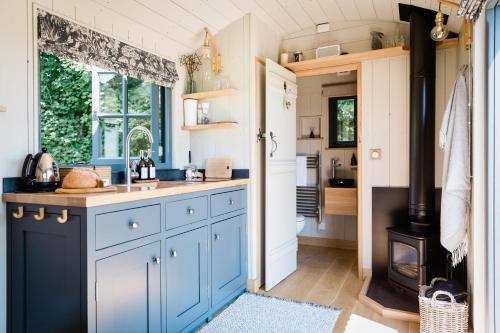 a kitchen with blue cabinets and a stove at Boutique Cornish Shepherd's Hut with Hot Tub in Launceston