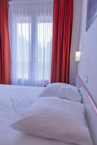 a bedroom with a white bed and a window at The Originals City, Relax'Otel & Spa, Le Barcarès in Le Barcarès