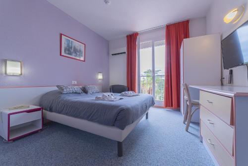 a bedroom with a bed and a desk and a window at The Originals City, Relax'Otel & Spa, Le Barcarès in Le Barcarès