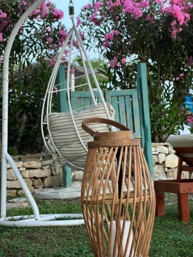 a swinging chair in a garden with pink flowers at Kallmi View Eco Rooms in Durrës