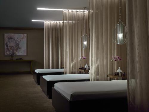 a row of beds in a room with white curtains at The Langham Huntington, Pasadena in Pasadena