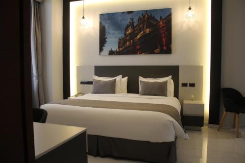a bedroom with a large bed and a painting on the wall at Hotel Boutique Casona de Santa Clara in Puebla