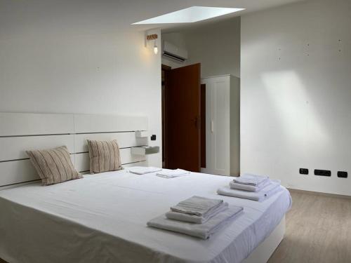 um quarto com uma cama branca e toalhas em Kibilù - Brebbia Bilocale con Piscina Parcheggio vicinanze Lago Maggiore em Brebbia