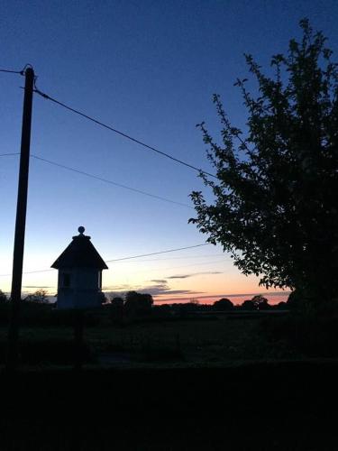 a barn in a field with the sunset in the background at The Shepherd's Hut with cozy logburner in Wrexham