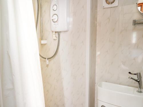 a white bathroom with a shower and a sink at Hawthorn Hut in Llanidloes