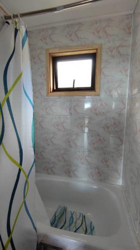 a bathroom with a bath tub with a window at CASAS Y CABAÑAS CUMBRES DEL SOL in Castro