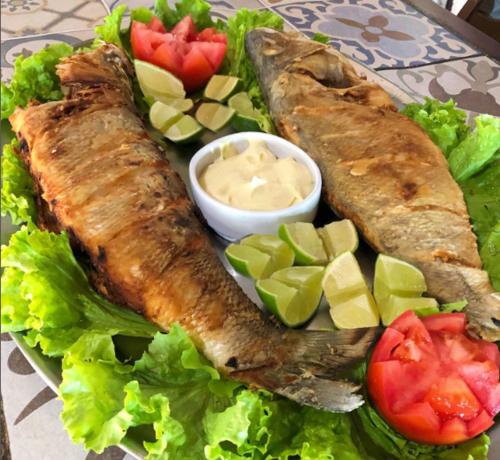 ein Teller mit Essen mit Fisch und Gemüse und Soße in der Unterkunft Pousada Maanaim in Ubatuba