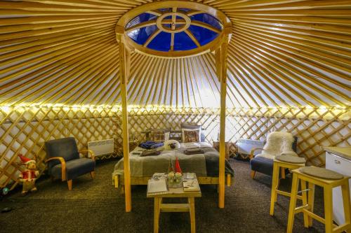 1 dormitorio en una yurta con 1 cama y sillas en Yurt District en Rovaniemi
