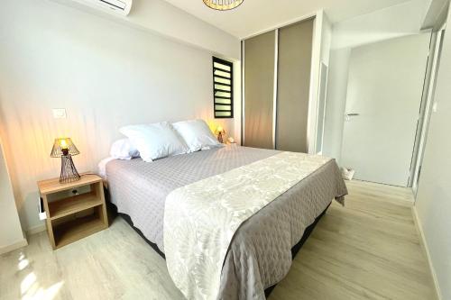 a bedroom with a bed and a table with a lamp at Mereani flat brand new condo in the center of Papeete in Papeete