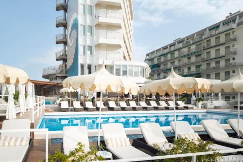 Hotel Delle Nazioni في ليدو دي يسولو: مسبح وكراسي ومظلات بجانب الفندق