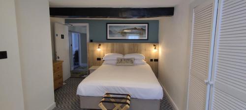a bedroom with a large bed with white sheets at Royal Oak Hotel in Rosthwaite