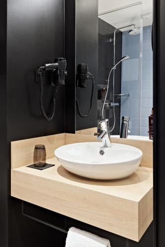 a bathroom with a white sink and a mirror at LÉGÈRE HOTEL Erfurt in Erfurt