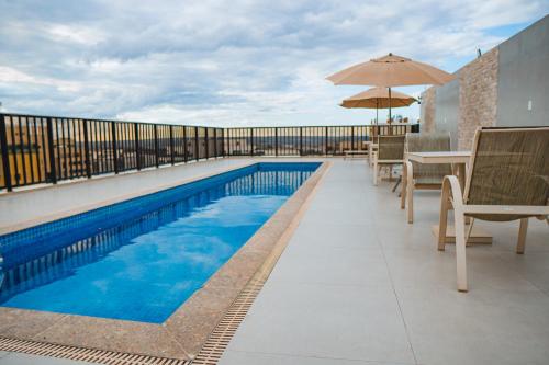 a swimming pool with chairs and an umbrella on a balcony at Nobile Suites Monumental in Brasilia