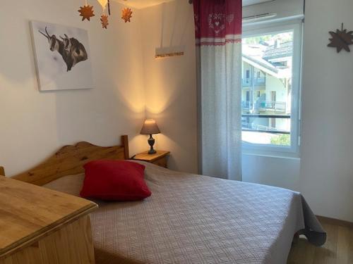 um quarto com uma cama com uma almofada vermelha em Appartement Brides-les-Bains, 3 pièces, 6 personnes - FR-1-512-148 em Brides-les-Bains