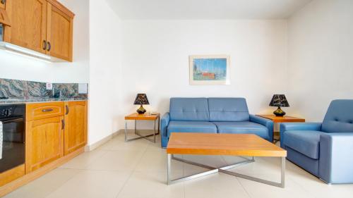 a living room with two blue couches and a table at AX Sunny Coast Resort & Spa in St Paul's Bay