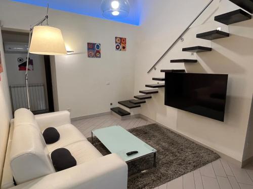 ein Wohnzimmer mit einem Sofa, einem TV und einer Treppe in der Unterkunft Il Nido Etrusco in Orvieto