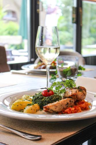 a plate of food on a table with a glass of wine at Forsthaus-Ferienhotel am Dobrock in Wingst