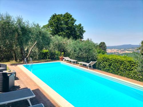 a swimming pool with two benches in a yard at Villa Fiorenzani in Radicondoli