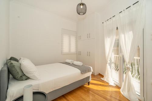 アテネにあるSunny And Cozy 2bd Apt 1 min from Marina Floisvosのベッドと窓のある白い寝室