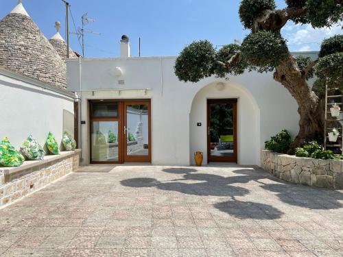 a white building with a door and a tree at Il trullo di nonno Licchio in Alberobello