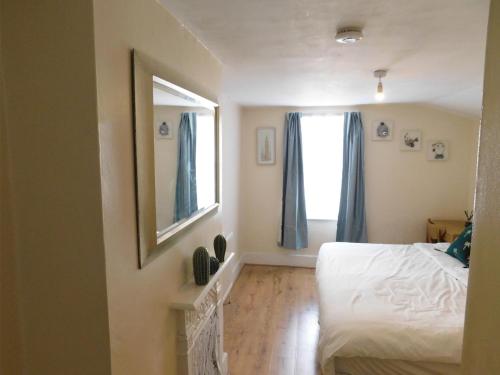Entire 4 bedroom Terrace house in London في لندن: غرفة نوم بسرير ابيض ومرآة