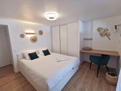 een slaapkamer met een wit bed en een bureau bij La petite Halte - Les Maisons de Madeleine in Bouguenais
