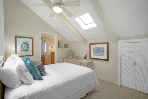 a bedroom with a white bed with a ceiling fan at Pali Ke Kua #233 in Princeville