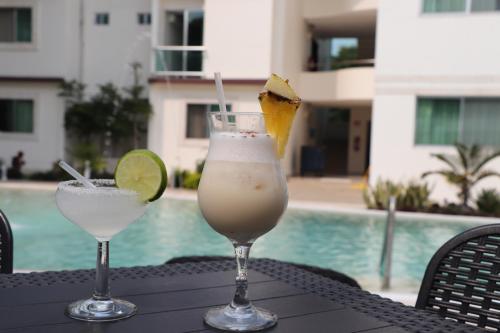 two cocktails sitting on a table next to a pool at Hotel Tulija Palenque in Palenque