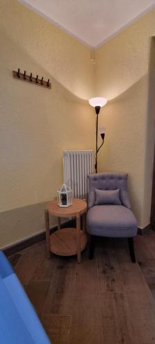 a room with a chair and a table and a lamp at Lo Noyer et les Roses in Saint Nicolas