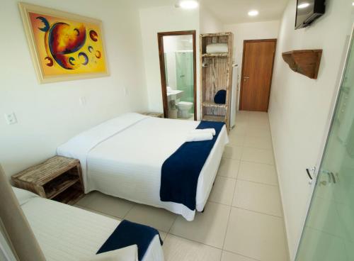 a hotel room with two beds and a bathroom at Apart Hotel Porto Kanoas in Bertioga