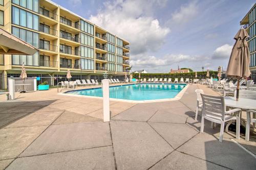 a pool with chairs and a table and a building at Welcoming Brigantine Condo with Ocean Views! in Brigantine