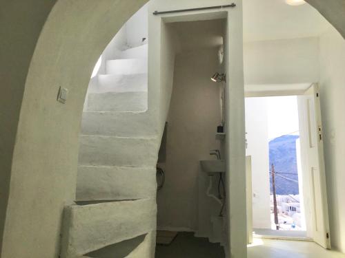 a white bathroom with a staircase leading up to a room at Sunset House in Serifos Chora