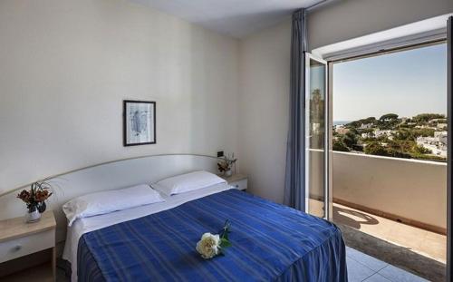 a bedroom with a bed with a blue blanket and a window at Relais Villa agave in Ischia