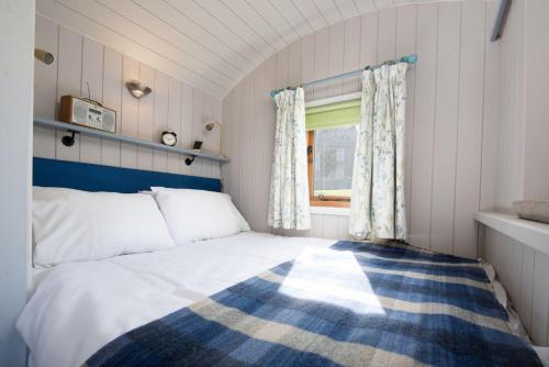 a bedroom with a bed and a window at Teasel Shepherd's Hut in Berwick-Upon-Tweed