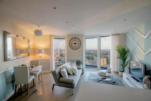 a living room with a couch and a clock on the wall at Amazing London City Skyline View & Transport Links in Barking