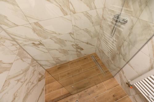 a shower in a bathroom with a marble wall at Sobe - Rooms Drvorez in Banja Luka