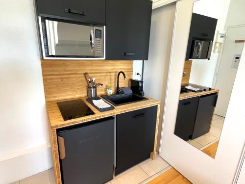 uma pequena cozinha com um lavatório e um micro-ondas em Studio République Centre NETFLIX inclus em Orléans