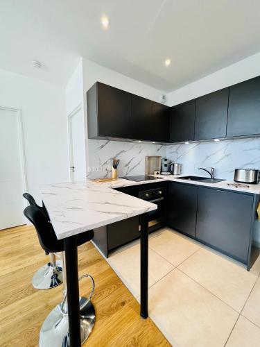 une cuisine avec des armoires noires et une table. dans l'établissement NB ARROWS Appartement de standing en hyper centre, à Chartres