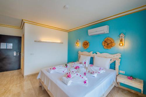 a bedroom with a white bed with pink flowers on it at Kaş Sun Glare Hotel in Kas