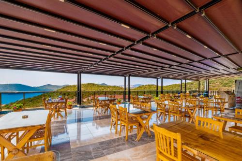a restaurant with tables and chairs and a view of the ocean at Kaş Sun Glare Hotel in Kas