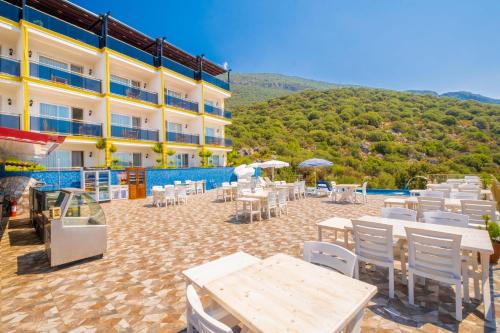 a patio with tables and chairs and a building at Kaş Sun Glare Hotel in Kas
