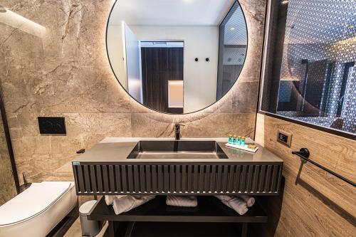 een badkamer met een wastafel, een toilet en een spiegel bij Marinus Beach Hotel in Marina