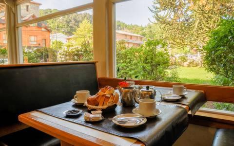 een tafel met een dienblad met eten en een raam bij Hotel Crismalu in San Martín de los Andes