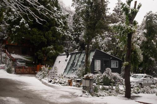 a house covered in snow in a yard at La Dorita cabaña de montaña in San Carlos de Bariloche