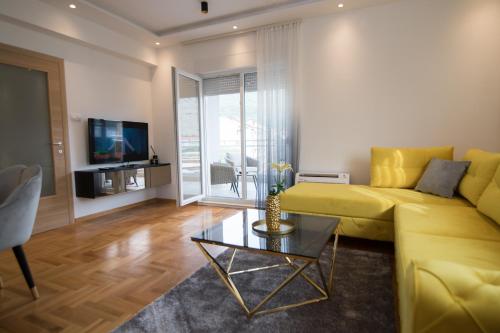 a living room with a yellow couch and a table at July in Trebinje
