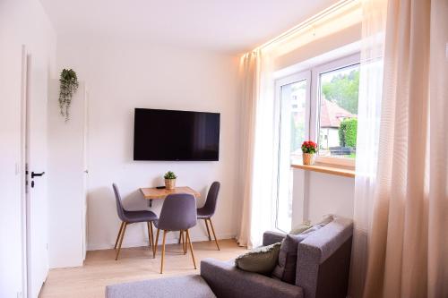 a living room with a table and chairs and a tv at Apartamenty Turystyczna 25 in Kudowa-Zdrój