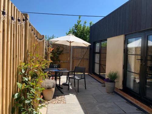 a patio with an umbrella and a table and chairs at The Burrow at Tankerton in Whitstable
