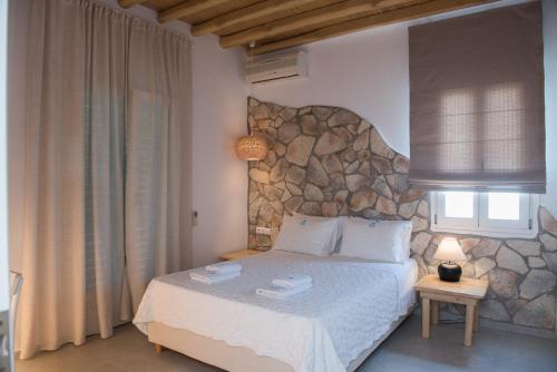 a bedroom with a bed with a stone wall at Villa Meliti in Platis Gialos